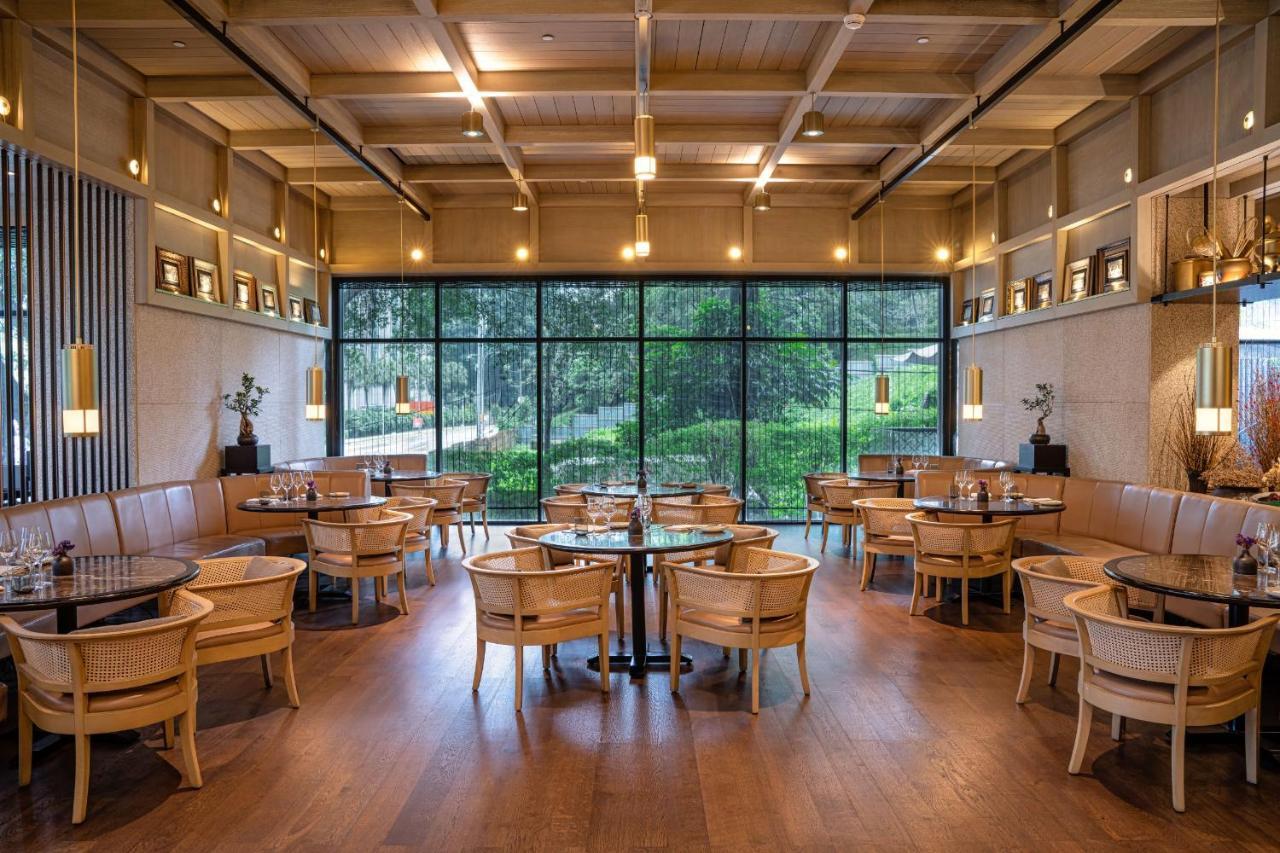The Ruma Hotel And Residences Kuala Lumpur Exterior photo The photo shows the interior of a modern restaurant. It features wooden flooring, large windows that let in natural light, and an open layout. The seating consists of round tables surrounded by chairs, along with some cushioned booths. The decor has 